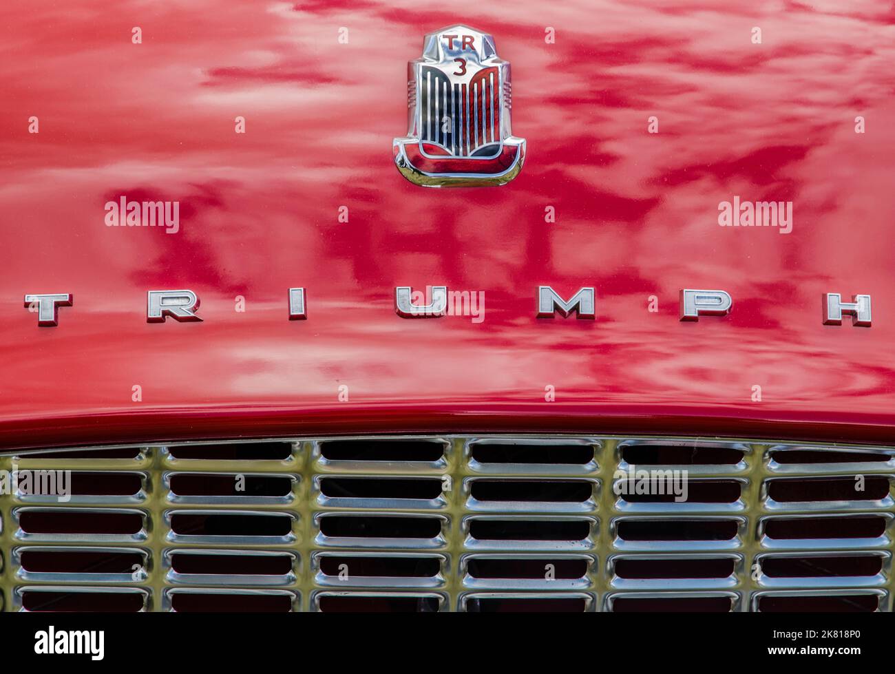 Vista frontal de un Triumph TR3 rojo que muestra las insignias cromadas y la rejilla del radiador Foto de stock