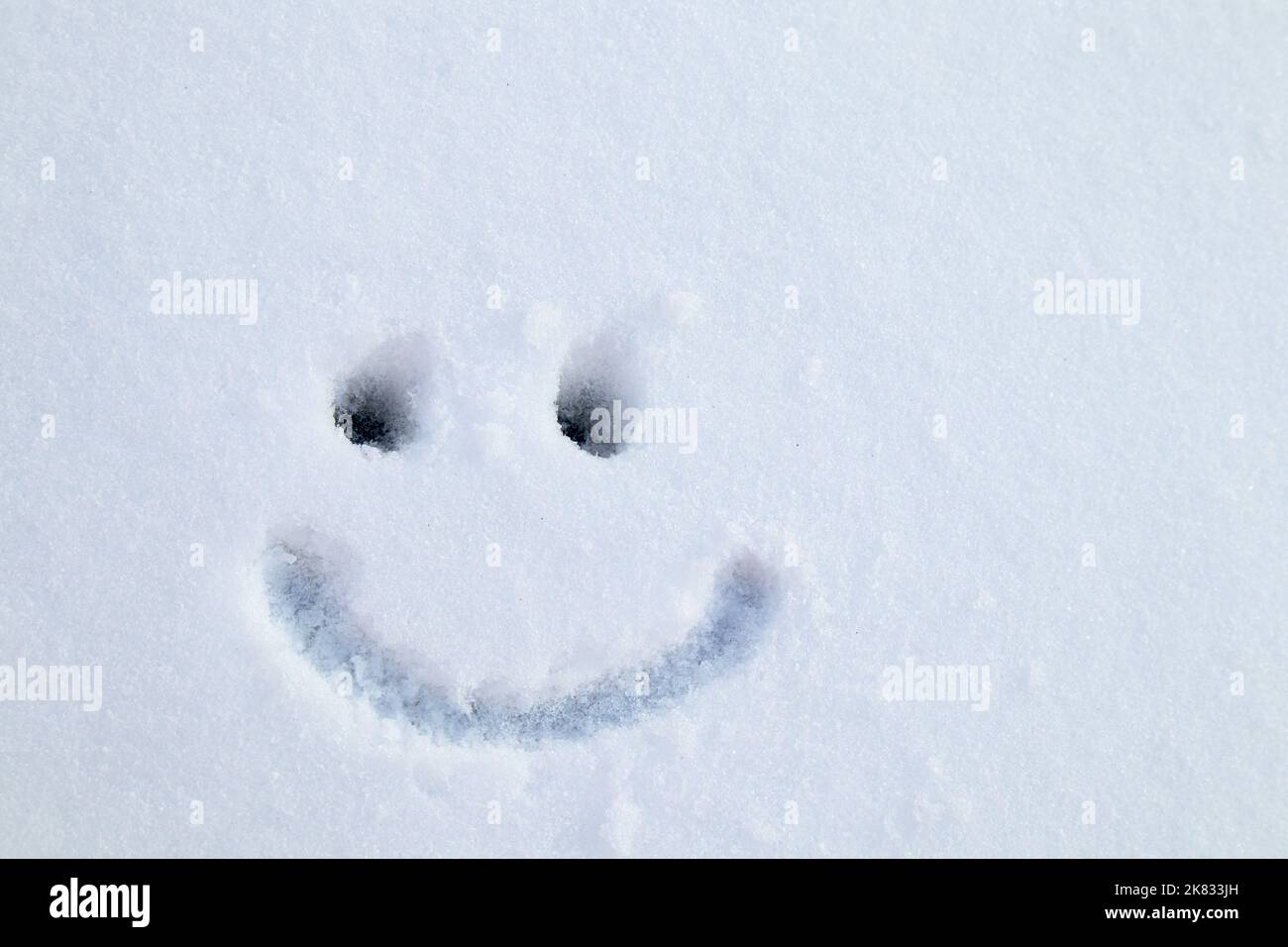 Figura Cara dibujada en la nieve, sonrisa y ojos, emociones. Postal Foto de stock