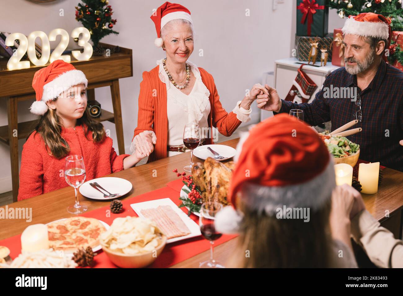¡Feliz Navidad! Una familia feliz está cenando en casa. Fiesta de celebración y compañerismo cerca del árbol Foto de stock