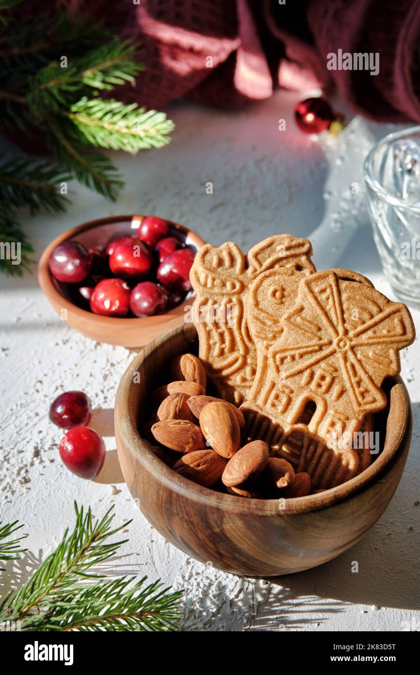 Speculoos o Spekulatius, galletas de Navidad, con bayas de arándano rojo, almendras sobre una mesa con toalla de cocina y ramitas de abeto. Dulces alemanes tradicionales Foto de stock