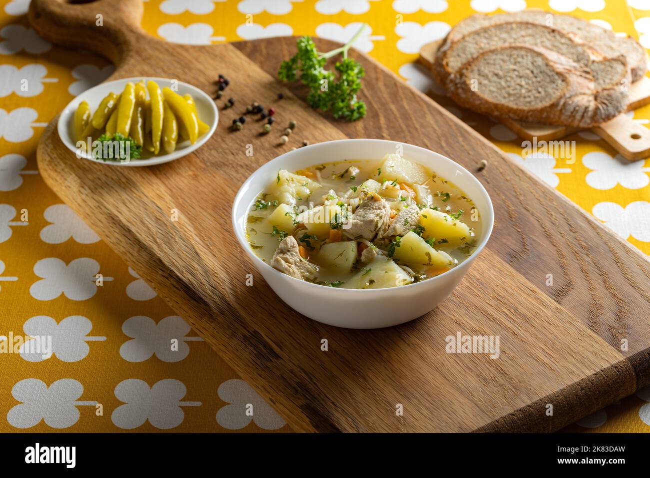Sopa de pollo con patatas y fideos sobre una tabla de madera rústica Foto de stock