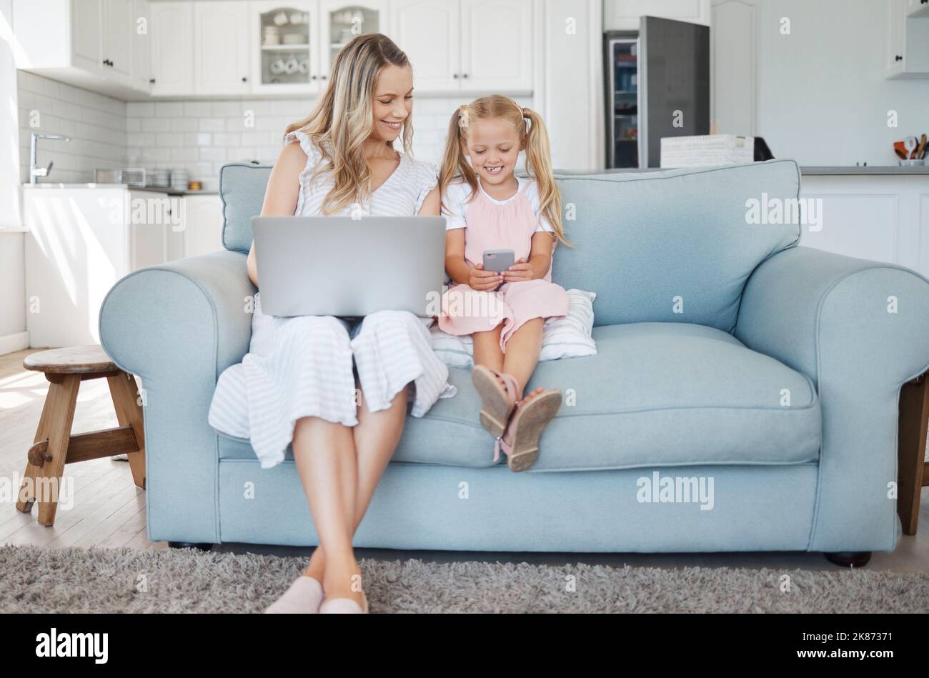 Tecnología, niño y madre aprendiendo en una aplicación móvil, trabajando en un portátil y feliz en Internet en el sofá de su casa. Chica y mamá Foto de stock