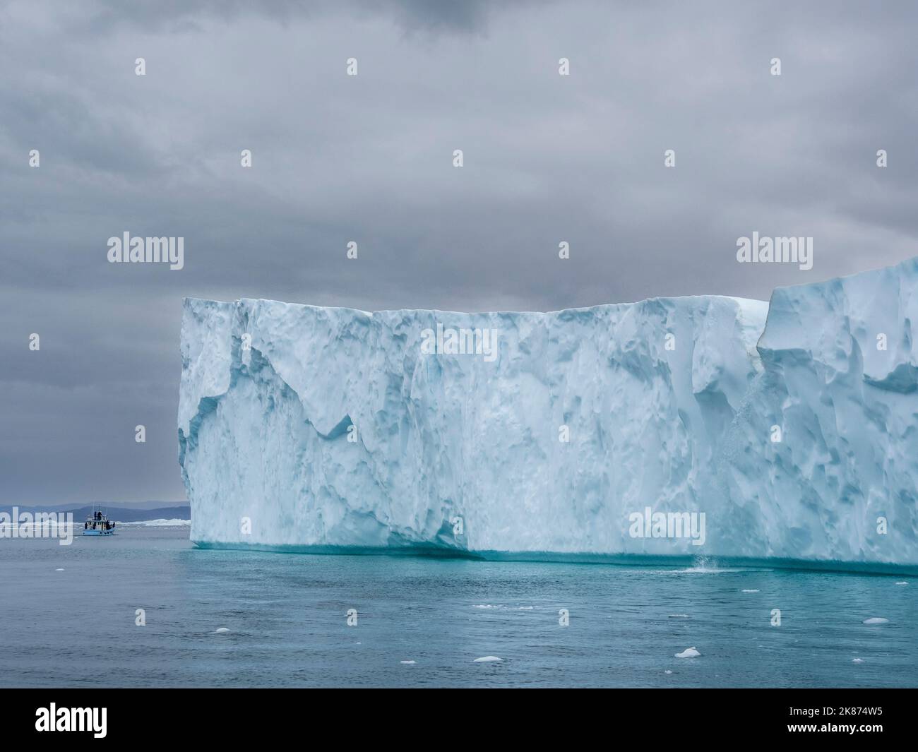 Los turistas que toman un tour de hielo en un pequeño barco viendo icebergs desde el Ilulissat Icefjord, justo a las afueras de Ilulissat, Groenlandia, Dinamarca, regiones polares Foto de stock