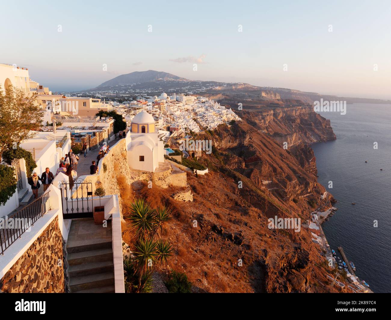 Ciudad de Fira al atardecer desde un camino costero con la costa de Caldera. Isla griega de las Cícladas de Santorini en el mar Egeo Foto de stock