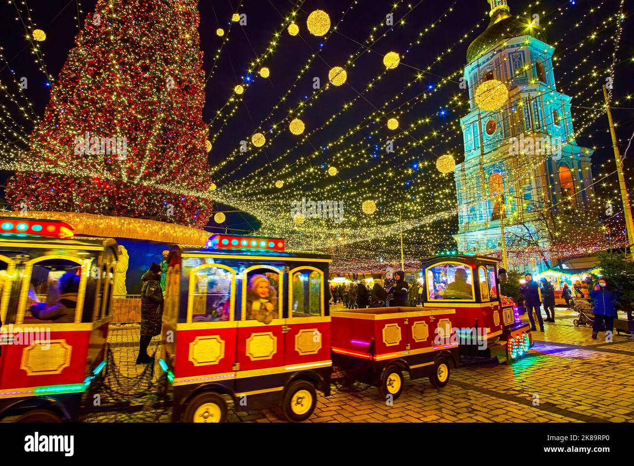 KIEV, UCRANIA - 28 DE DICIEMBRE de 2021: El tren turístico de color, a caballo alrededor de los puestos de la Feria de Navidad y el árbol de Navidad en la Plaza de Sofía, en diciembre Foto de stock