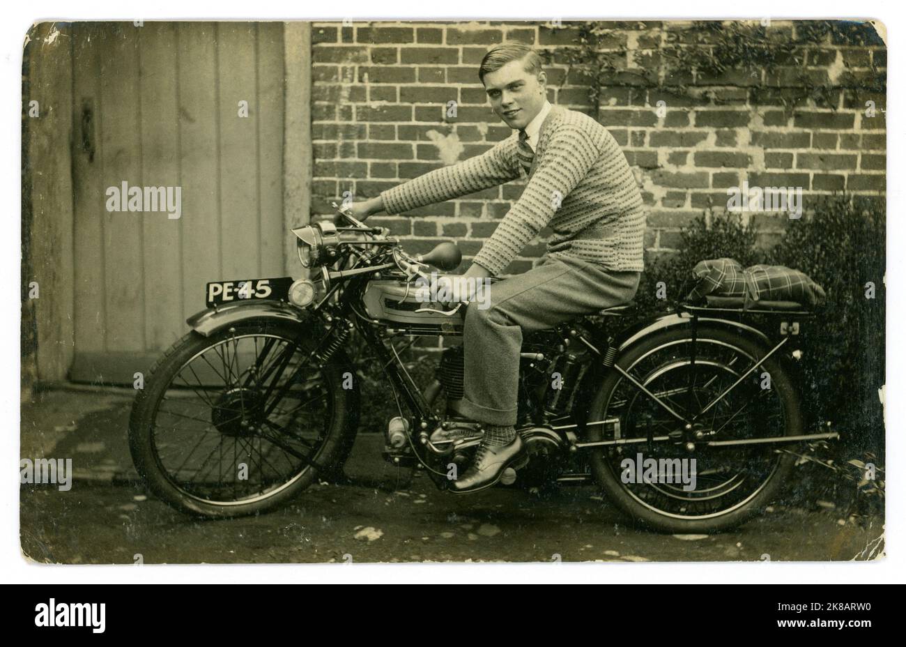Original de la era de 1920 de feliz orgulloso joven o adolescente tardío, sentado a un paso de lo que parece una nueva motocicleta Triumph, Guildford registration, Surrey, Inglaterra, Reino Unido Foto de stock