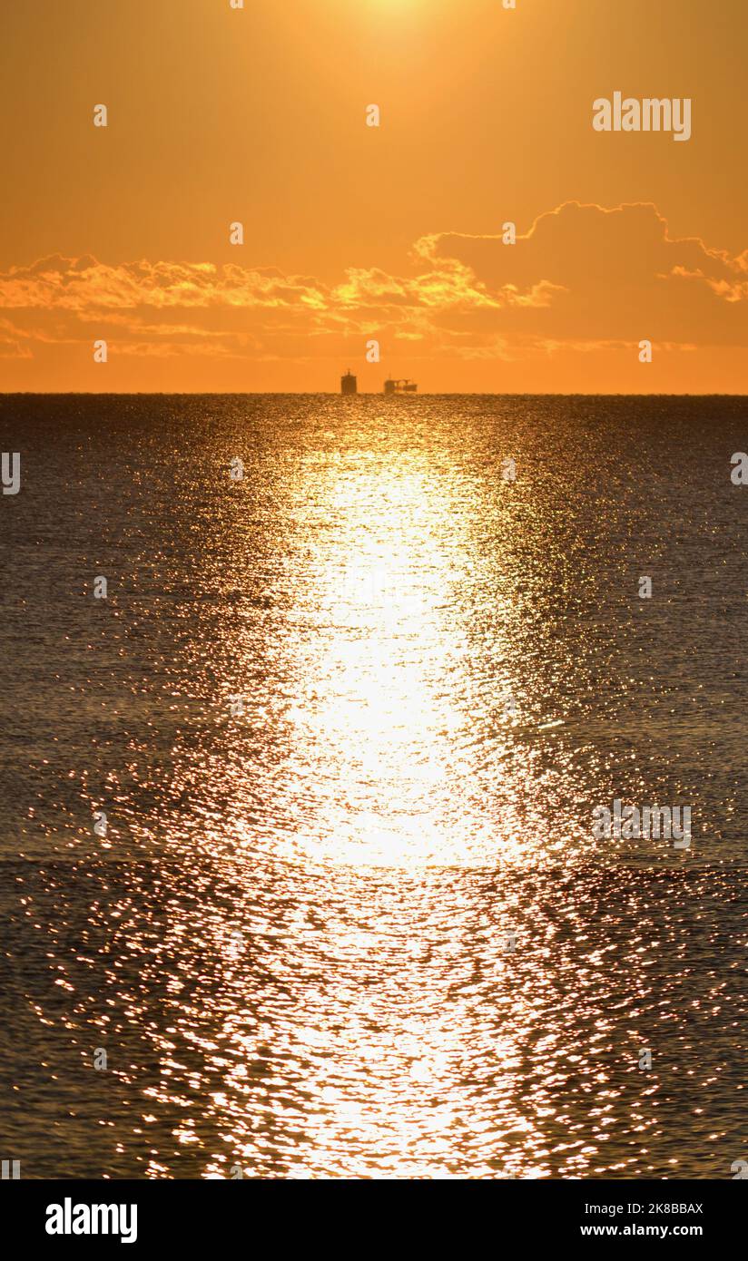 Dos siluetas de un tanquero en la línea del horizonte en el mar y un sendero soleado en la superficie del mar. Paisaje marino, paisaje marino. Fondo natural Foto de stock