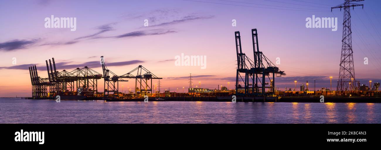 El concurrido puerto de Amberes muestra un horizonte de grúas y buques portacontenedores al atardecer Foto de stock