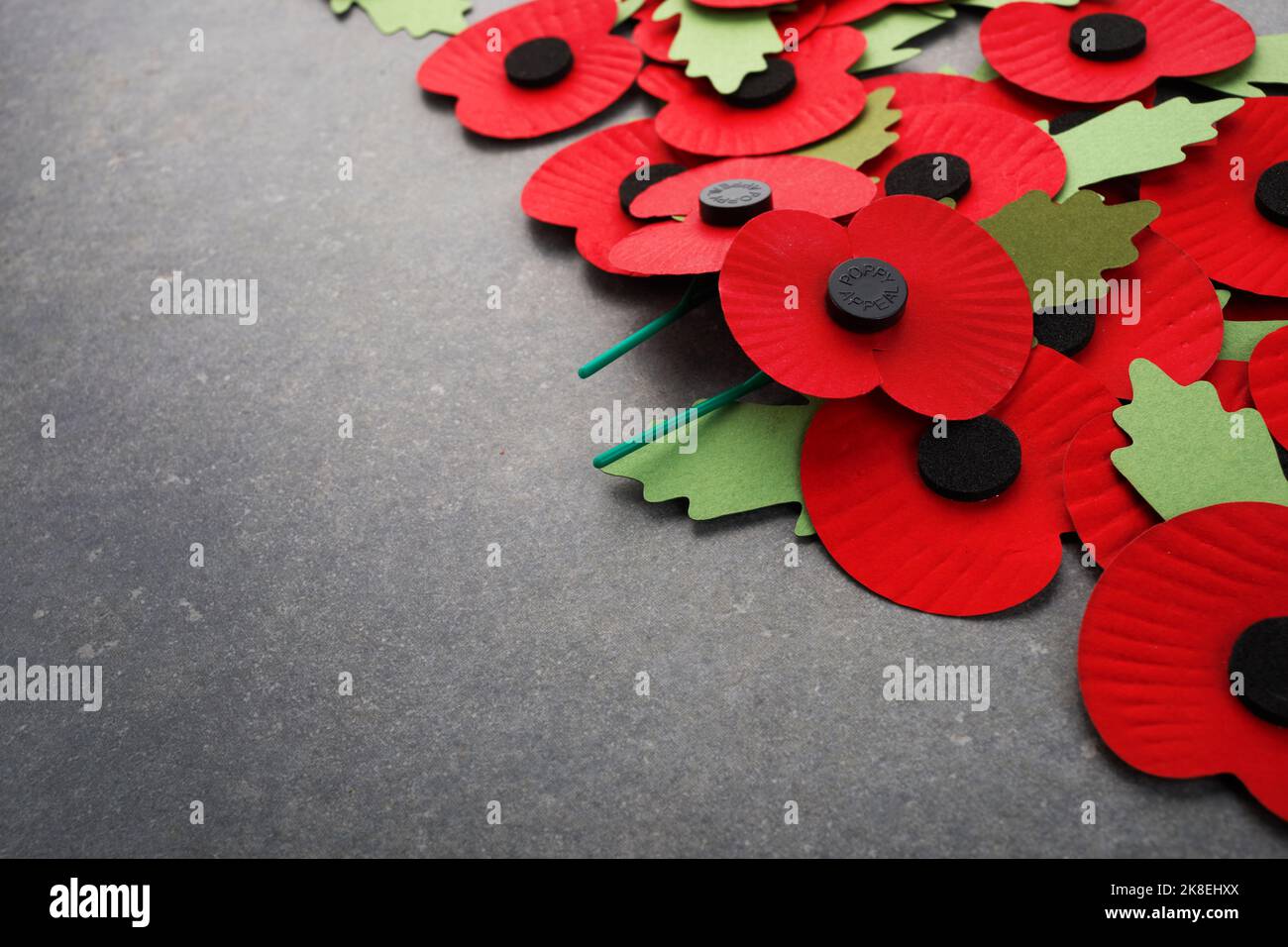 Día del recuerdo de la Guerra Mundial. Amapolas de papel rojo sobre fondo de piedra oscuro Foto de stock