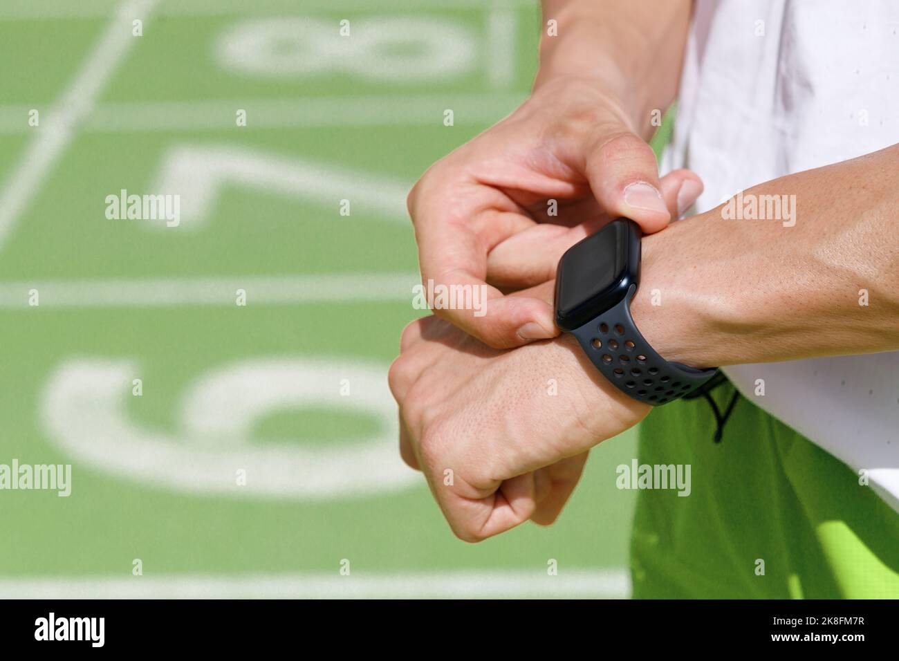 Hombre comprobando la hora en el reloj inteligente en la pista deportiva Foto de stock