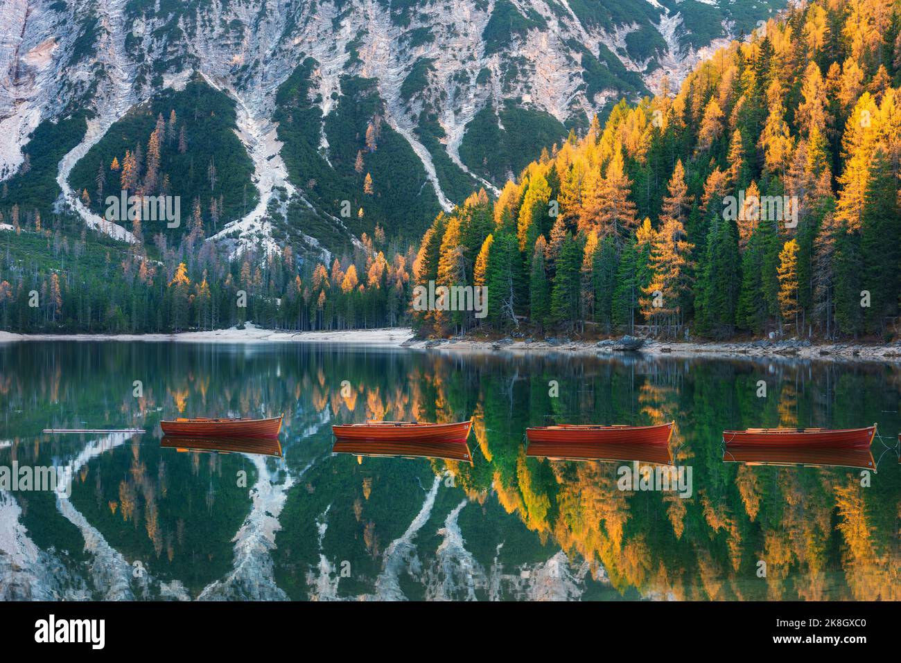 Barcos de madera roja en el lago Braies al amanecer en otoño en Dolomitas Foto de stock