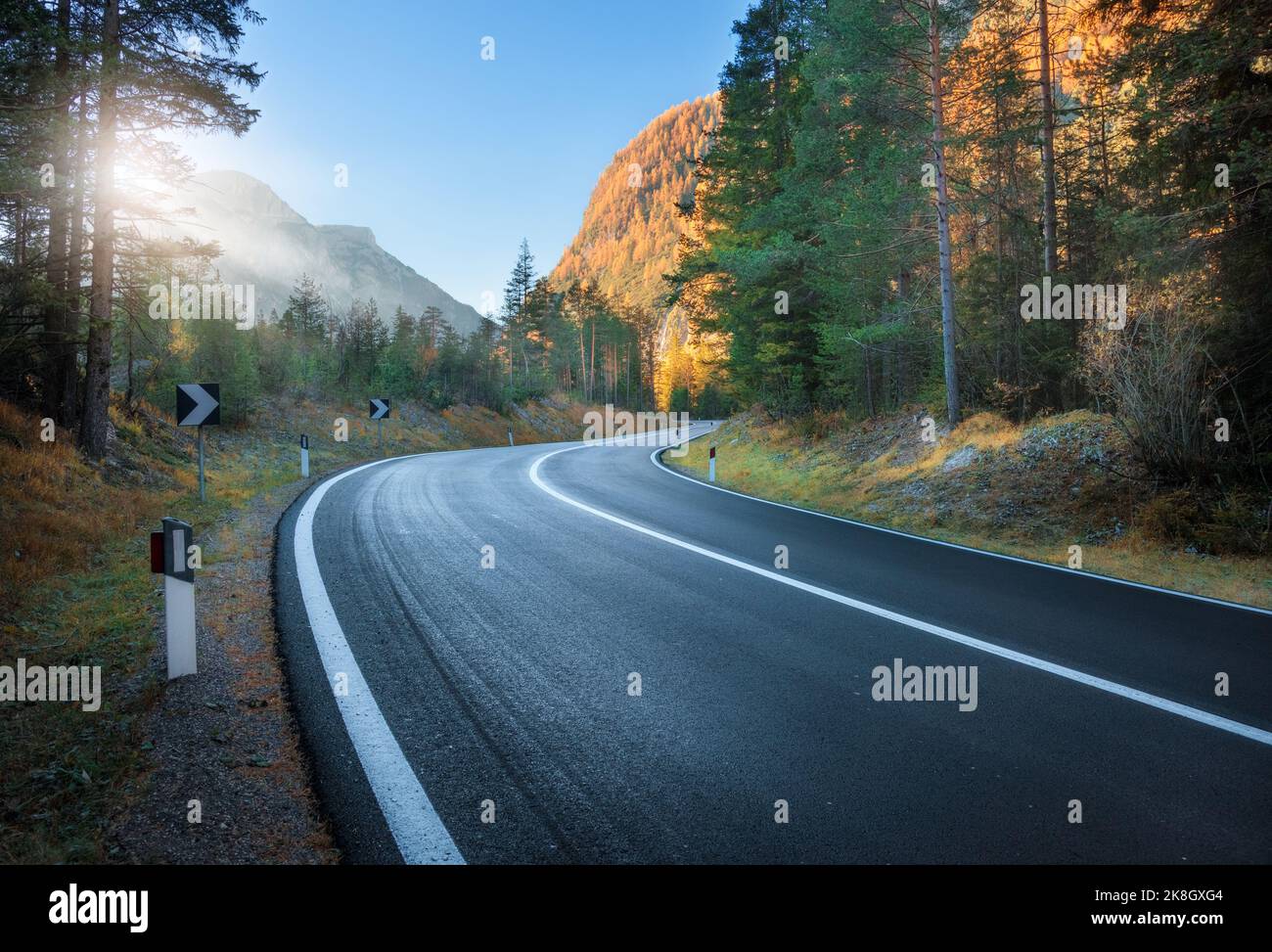Carretera en el bosque de otoño al atardecer en Dolomitas, Italia Foto de stock