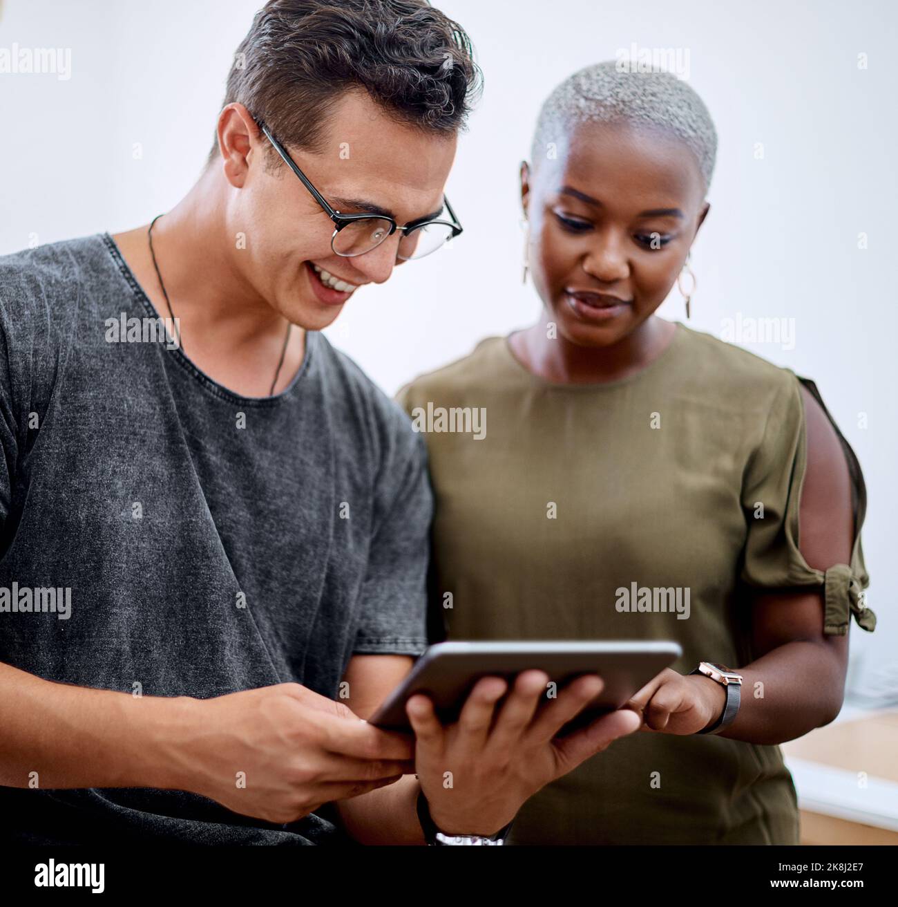 Es el compromiso de un equipo lo que importa. Dos empresarios que trabajan juntos en una tableta digital en una oficina. Foto de stock