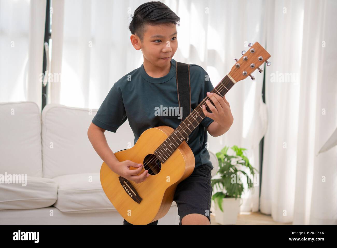 Chico asiático tocando guitarra sentado fotografías e imágenes de alta  resolución - Alamy