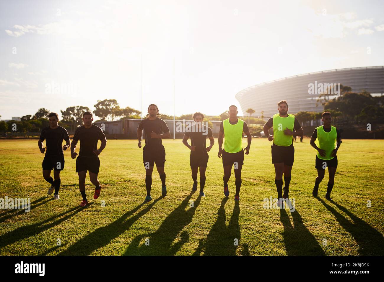 Corremos todos los días. Tiro completo de un grupo diverso de deportistas que se calientan antes de jugar al rugby durante el día. Foto de stock