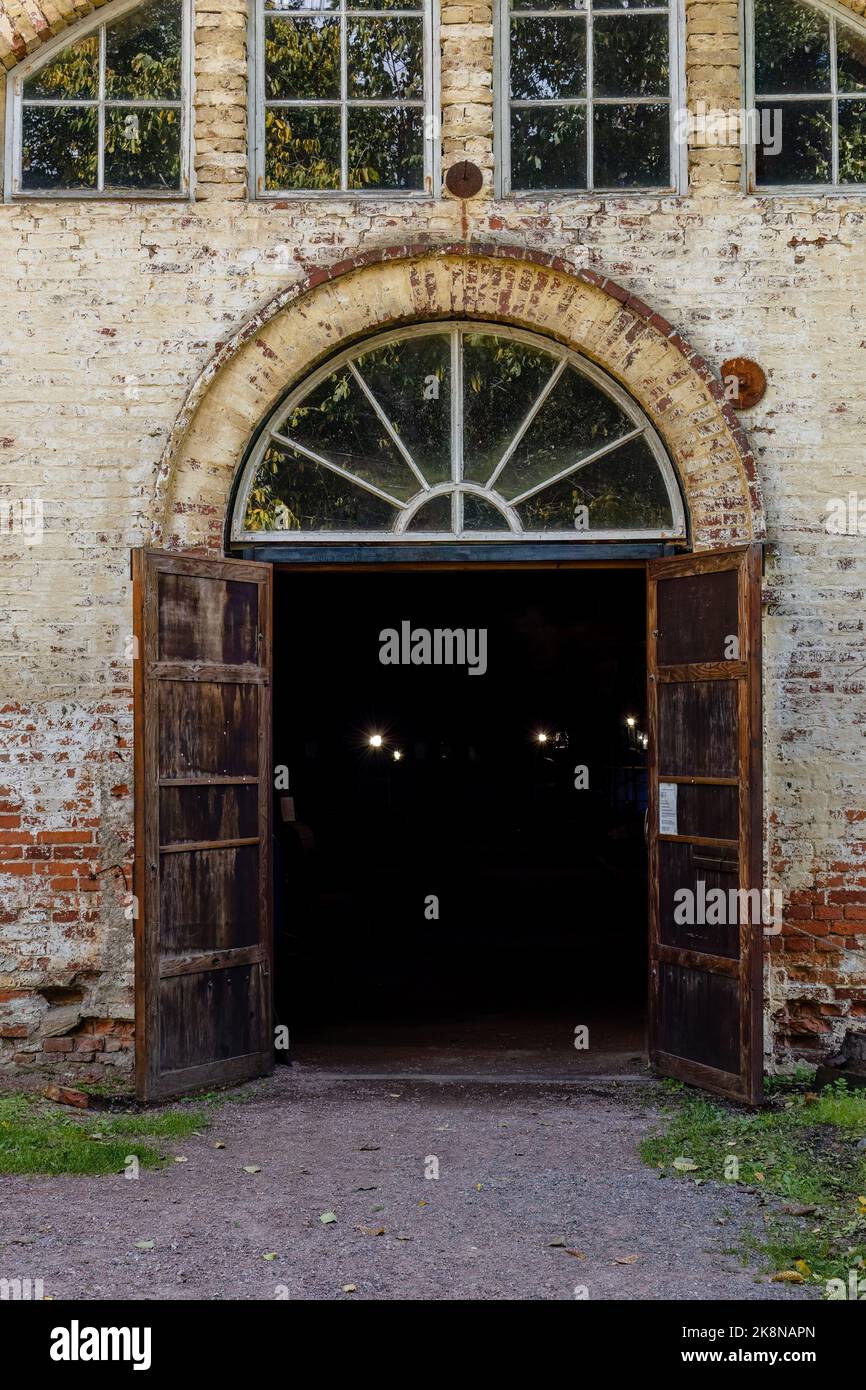 Puerta oscura con puertas de madera en un antiguo edificio de ladrillo Foto de stock