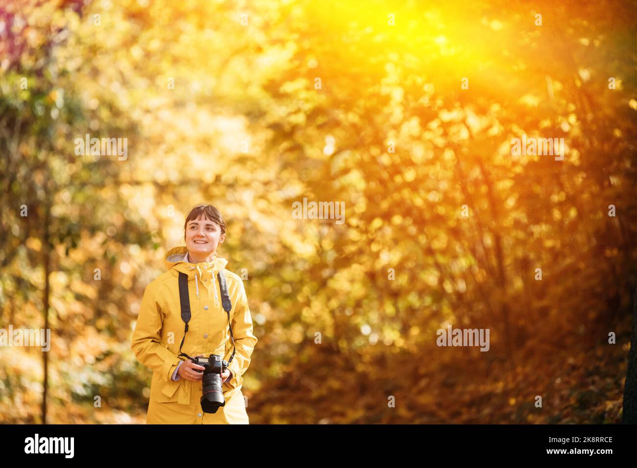 Mujer turística Caminando y tomando fotos en el bosque. Lady fotografió la naturaleza. Joven mujer sonriente feliz bastante caucásica en el camino en el bosque de otoño Foto de stock