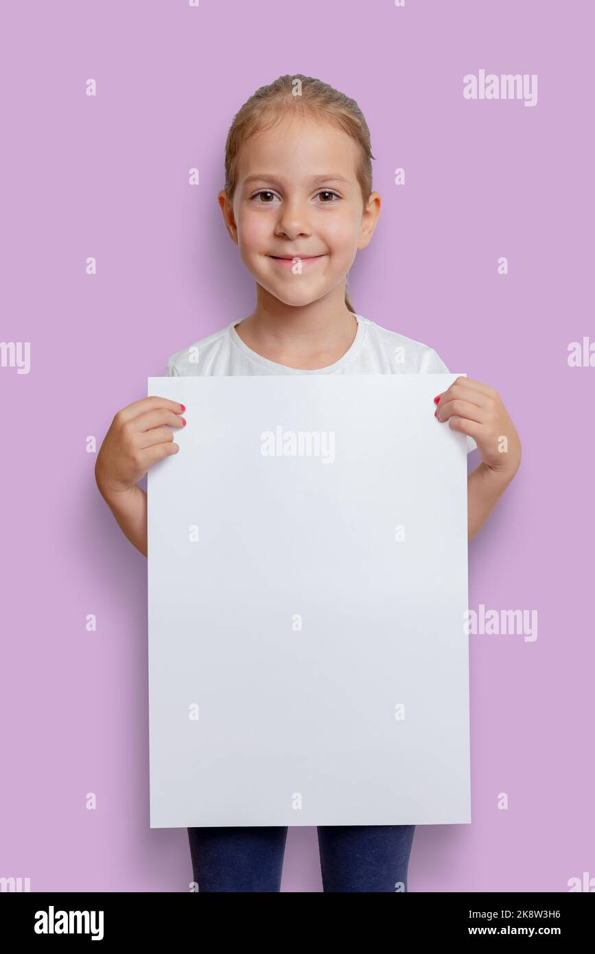 Chica sosteniendo un póster A3 vertical vacío en blanco para maqueta, anuncio o presentación de texto Foto de stock