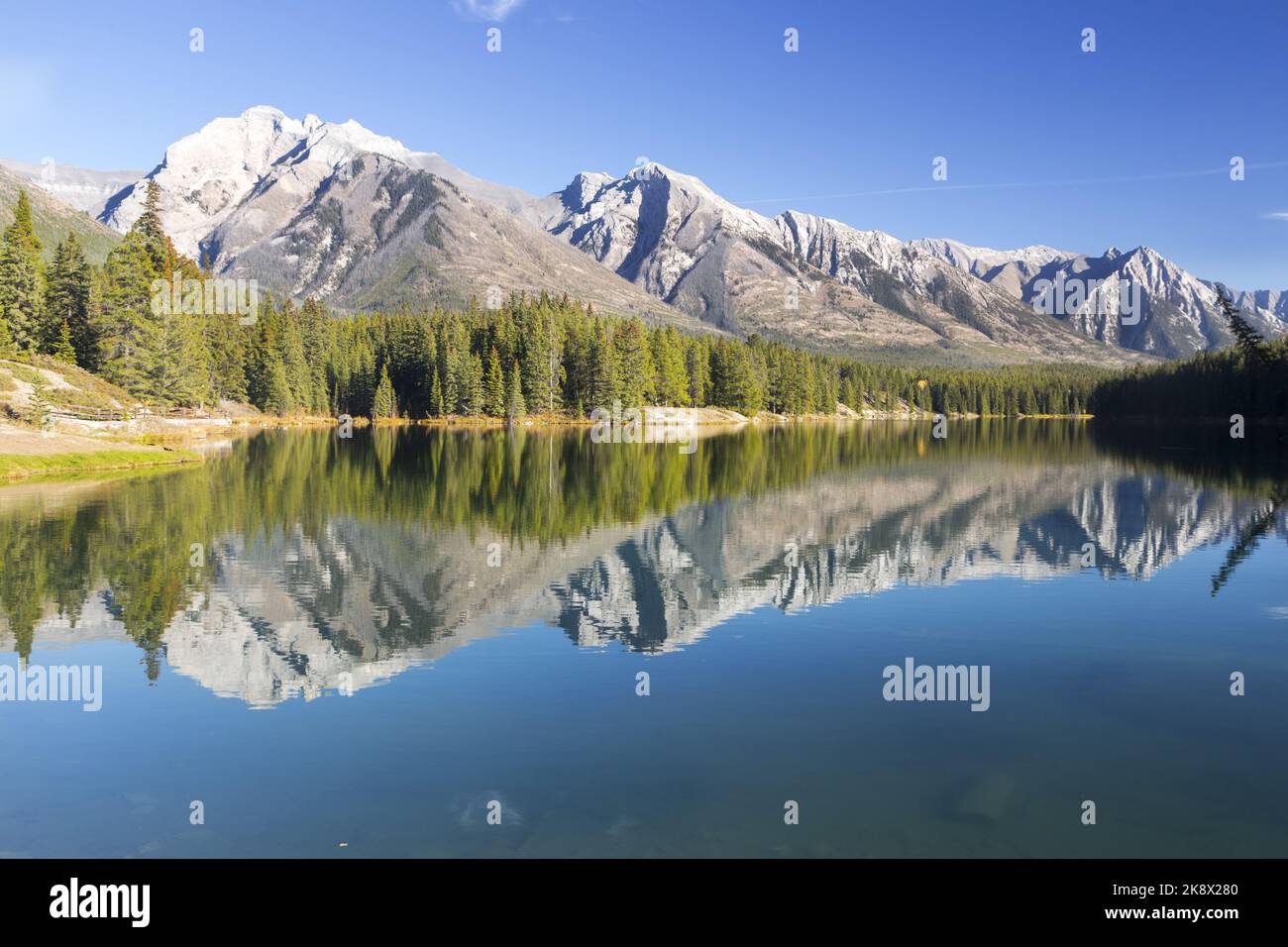Los árboles de la cadena montañosa y del bosque verde se reflejan en el agua tranquila del lago. Paisaje otoñal panorámico de Blue Sky Parque Nacional Banff, Montañas Rocosas canadienses Foto de stock