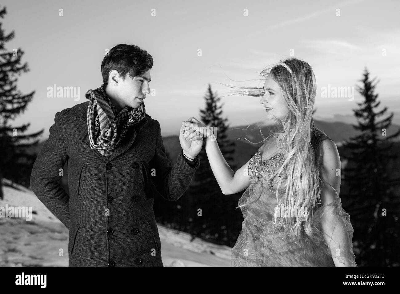 Una foto en blanco y negro de hombre con estilo en traje y joven dama en vestido de moda pose para la cámara en el valle en invierno Foto de stock