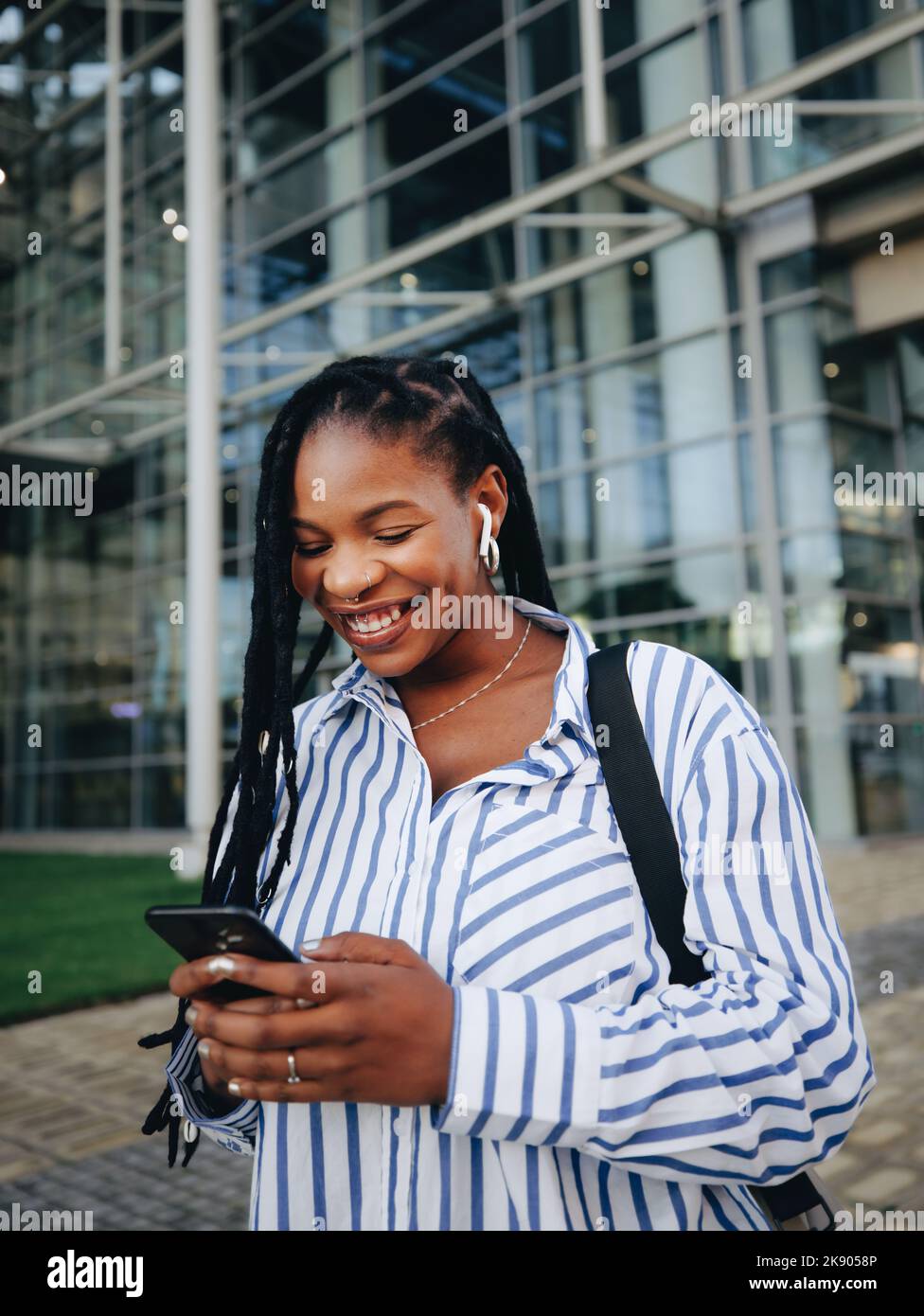 Mujer joven segura con ropa elegante sport sonriendo mientras estás de pie  cerca de su lugar de trabajo Fotografía de stock - Alamy