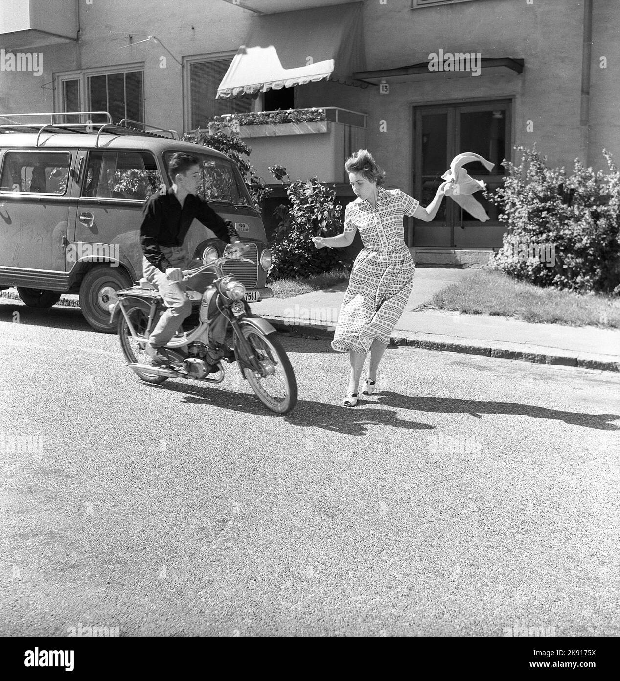 Adolescentes de los 1950s. Un adolescente está conduciendo su moto y una mujer parece que sale delante de él en la calle sin mirar con cuidado. Suecia 1958 ref CV79 Foto de stock