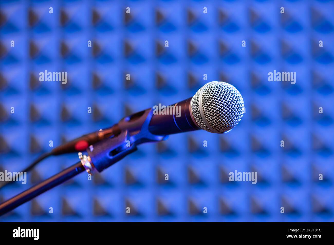 Enfoque suave de micrófono profesional montado en soporte contra pared azul insonorizada en estudio de grabación Foto de stock