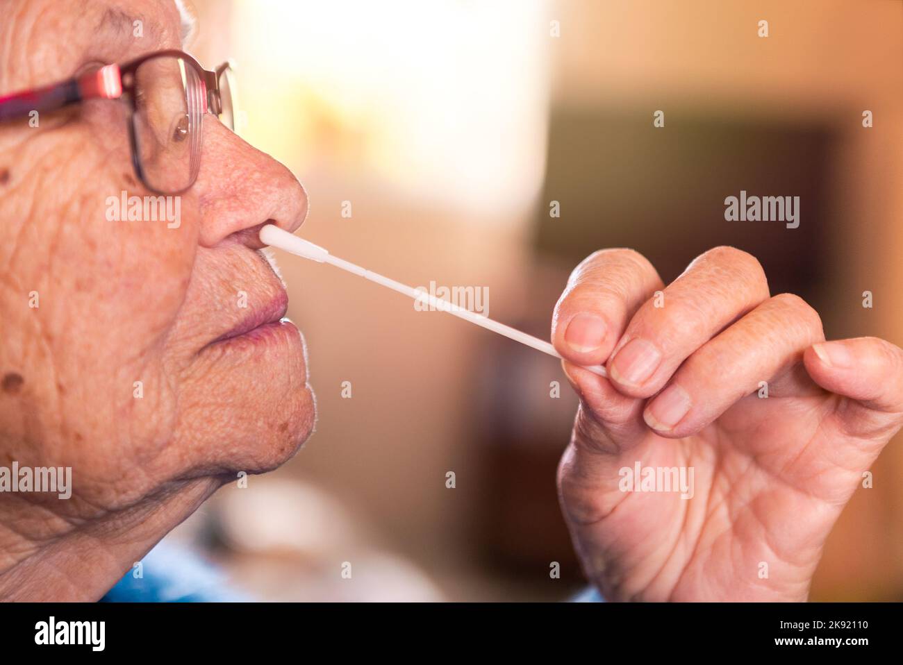 Retrato de una anciana haciéndose pruebas caseras para Covid19 con el kit de antígeno. Abuela caucásica que introduce un palito nasal para verificar la infección Foto de stock