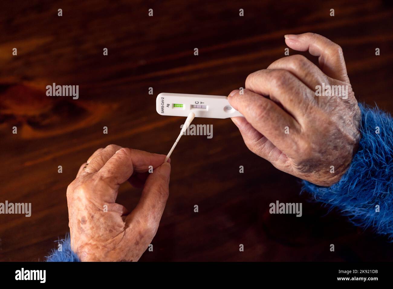 Primer plano de la mano de una anciana con un dispositivo de prueba positivo para Covid19. Abuela caucásica mostrando una prueba rápida de coronavirus enfermo en casa. Abuela Qu Foto de stock