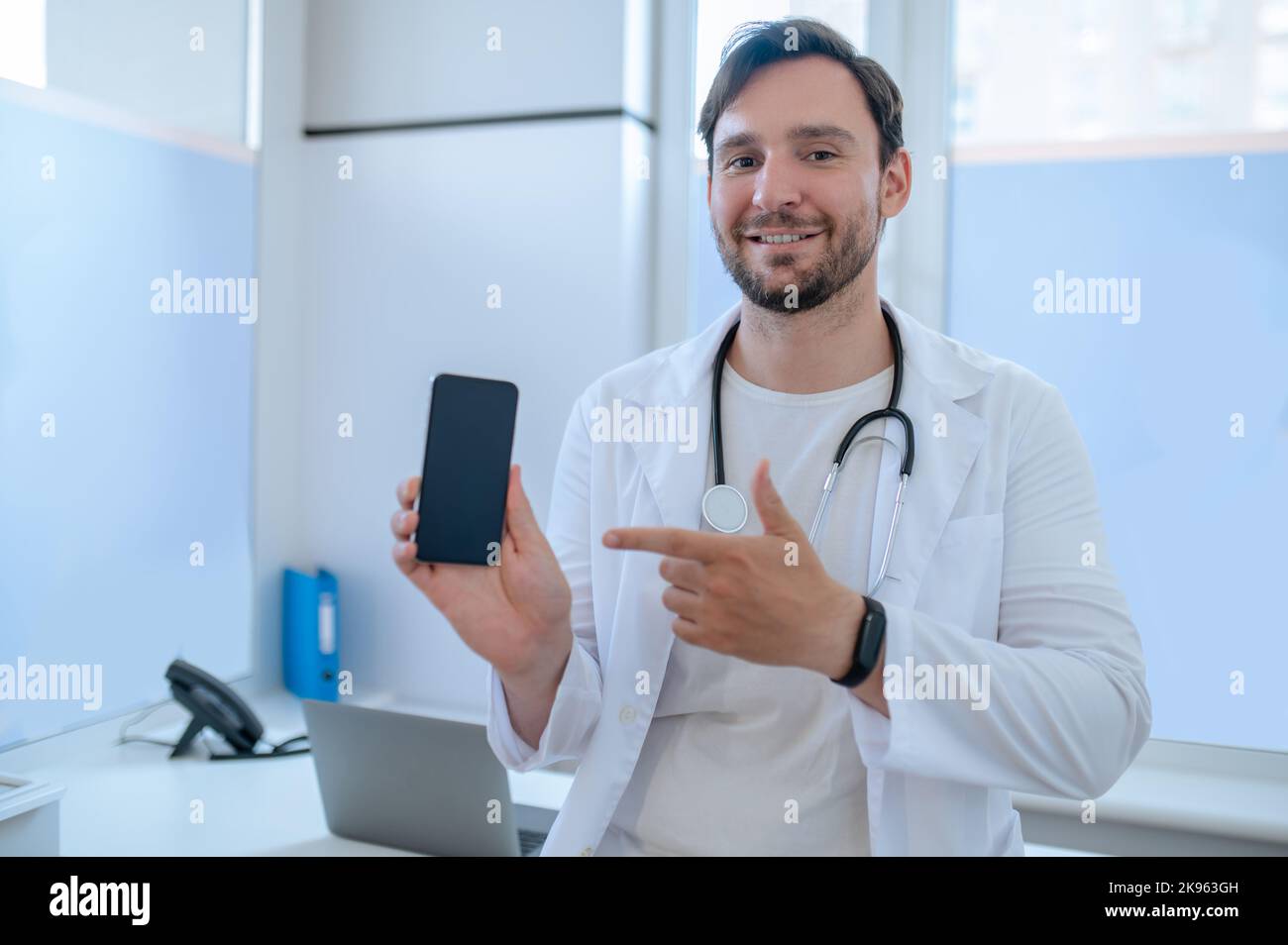 Médico alegre con el smartphone en la mano Foto de stock