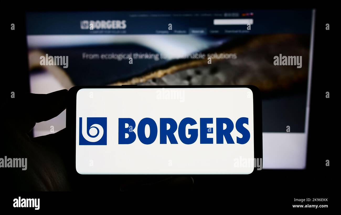 Persona que sostiene el teléfono móvil con el logotipo de la empresa automovilística alemana Persona que sostiene el teléfono móvil con el logotipo de la empresa automovilística alemana