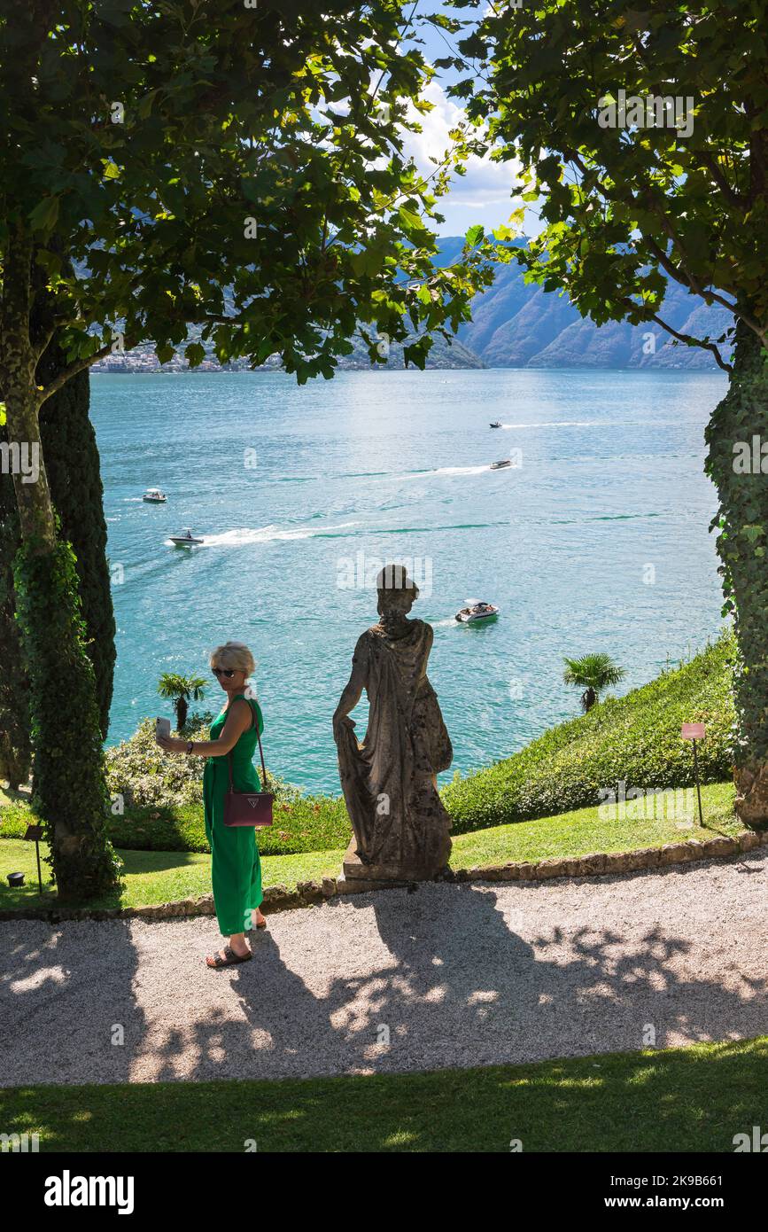 Turismo femenino, vista en verano de una mujer tomando una foto de sí misma con el telón de fondo del Lago Como, Lombardía, Italia Foto de stock