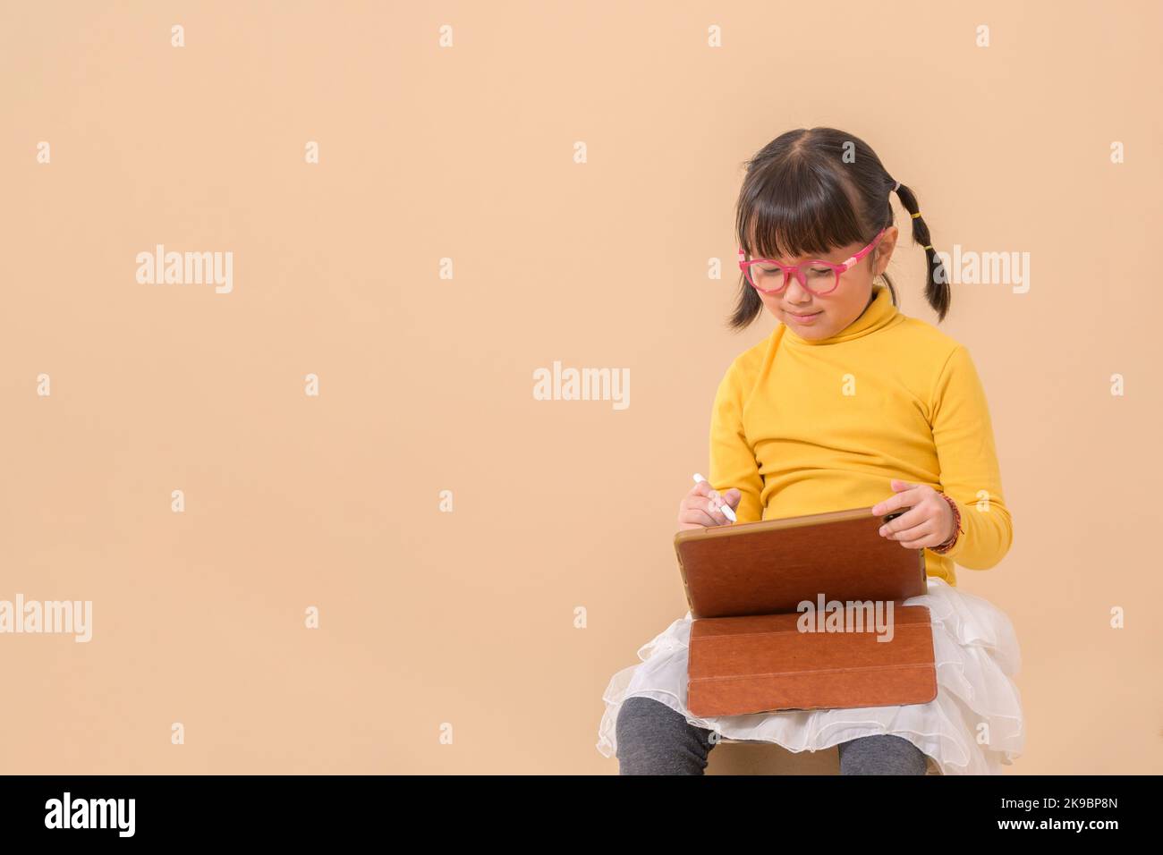 chica asiática sonriente sosteniendo y usando la tableta escribiendo o dibujando con la pluma digital. Espacio de copia libre aislado Foto de stock