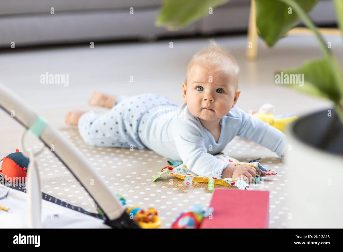 Lindo bebé niño jugando con los juguetes colgando arco en la colchoneta en el hogar Actividad del bebé y centro de juego para el desarrollo infantil temprano. Bebé jugando en casa Foto de stock