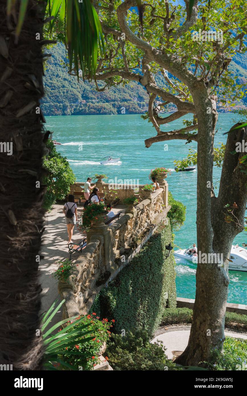 Villa del Balbianello, vista en verano de los turistas en la pintoresca terraza junto al lago que forma parte de los jardines de Villa del Balbianello, Lago Como, Italia Foto de stock