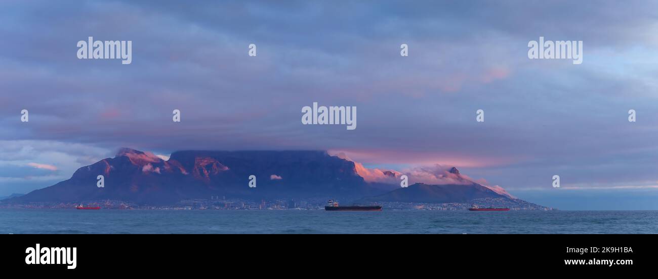 Vista emblemática de la bahía de Table en Table Mountain y Ciudad del Cabo en un día nublado al atardecer desde Bloubergstrand en Western Cape. Sudáfrica. Foto de stock