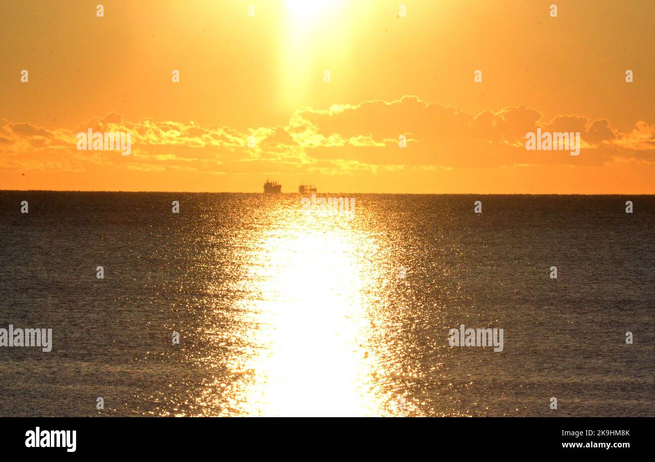 Dos siluetas de un tanquero en la línea del horizonte en el mar y un sendero soleado en la superficie del mar. Paisaje marino, paisaje marino. Fondo natural Foto de stock