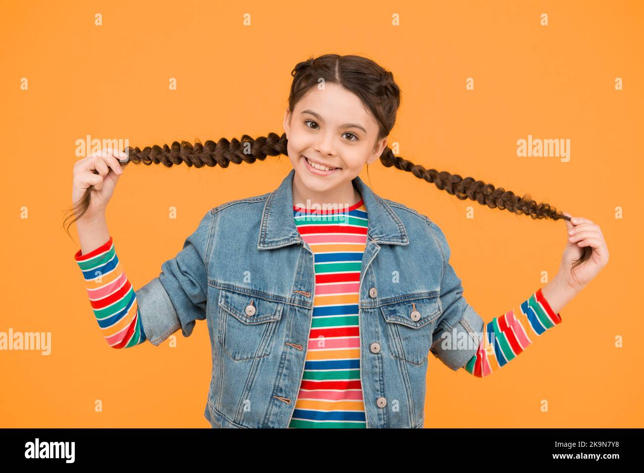 Feliz niña con trenzas llevar ropa vaquera, concepto de ropa para niños  Fotografía de stock - Alamy