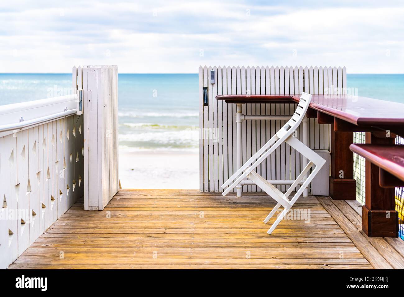 Seaside, Florida con un pabellón de madera blanca con vistas a las olas de agua del Golfo de México y sillas de cafetería de restaurante, mesas por valla Foto de stock