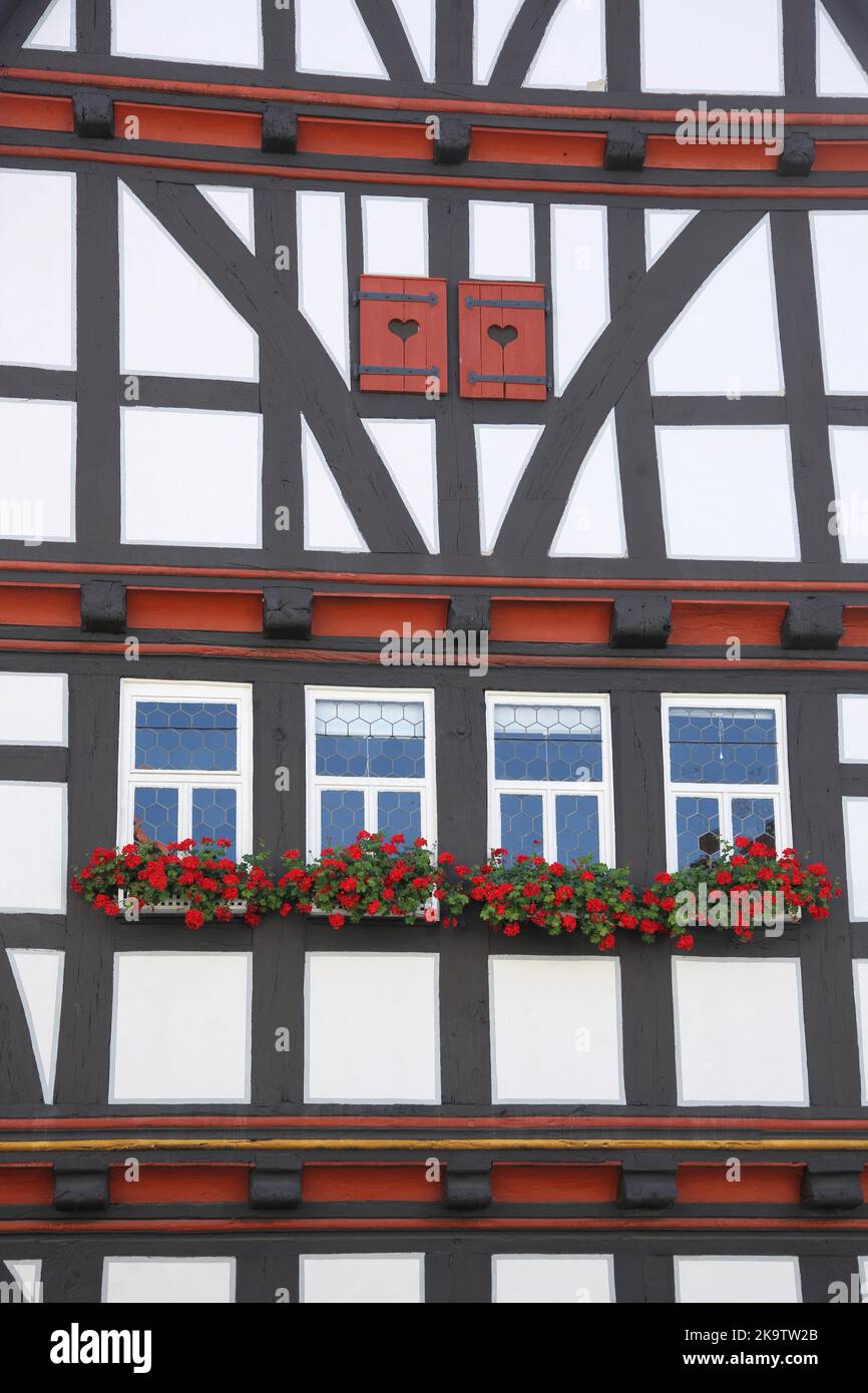 Idílico pared de la casa con persianas y decoración de flores del histórico ayuntamiento, idilo, obturador, en forma de corazón, Schotten, Vogelsberg, Hesse, Alemania Foto de stock