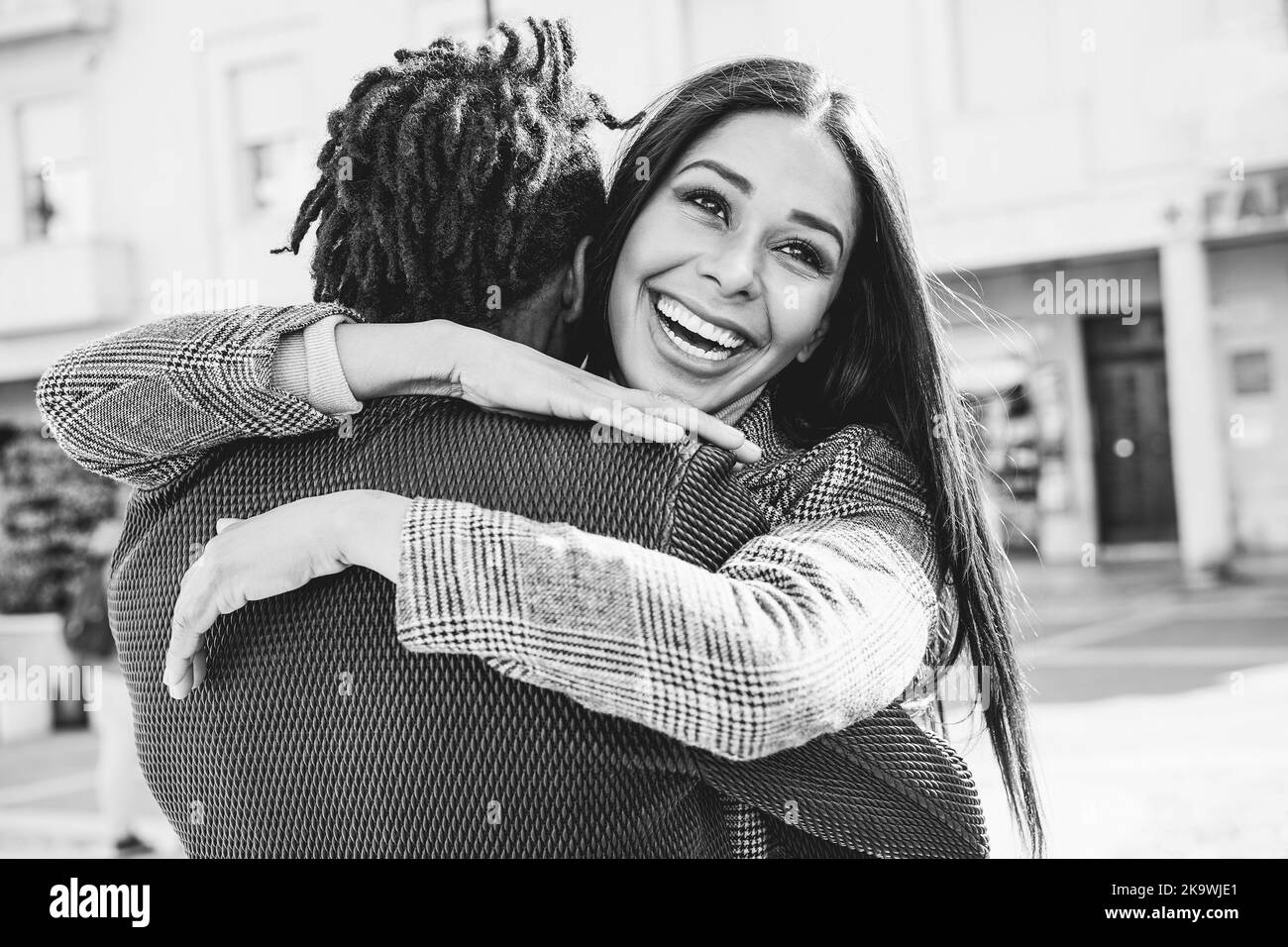 Feliz pareja africana divertirse abrazando al aire libre en la ciudad - centrarse en la cara de la chica - edición en blanco y negro Foto de stock