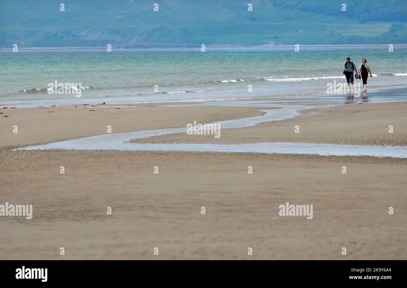 pareja caminando descalzos en las olas en porth neigwl, tyn don beach wales Foto de stock