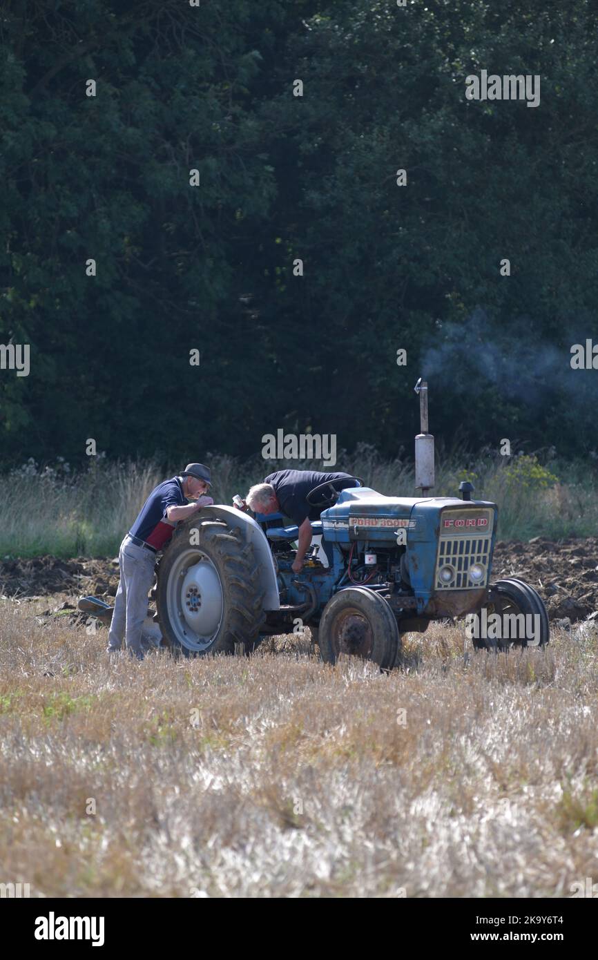 dos hombres ajustando el antiguo tractor de época en el campo de rastrojo brampton suffolk inglaterra Foto de stock