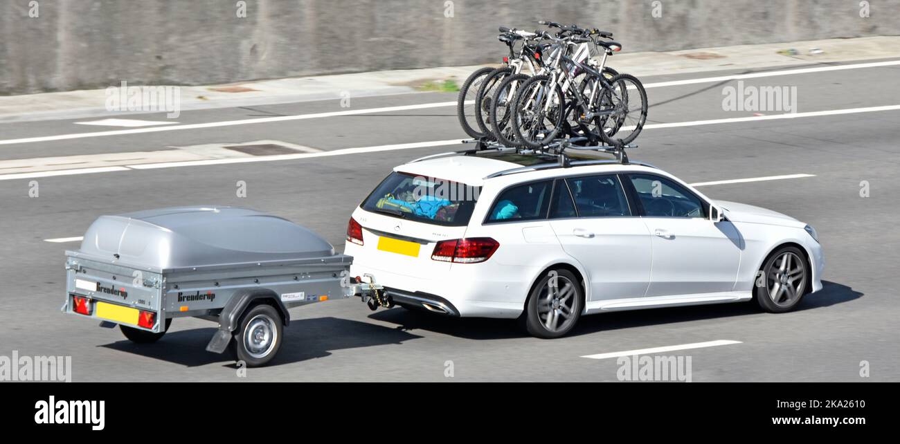 Portaequipajes fijado en un vehículo Mercedes blanco Vista lateral Transporte de bicicletas ciclistas y arrastre de un remolque Brenderup 1205 cubierto por carretera de autopista del Reino Unido Foto de stock