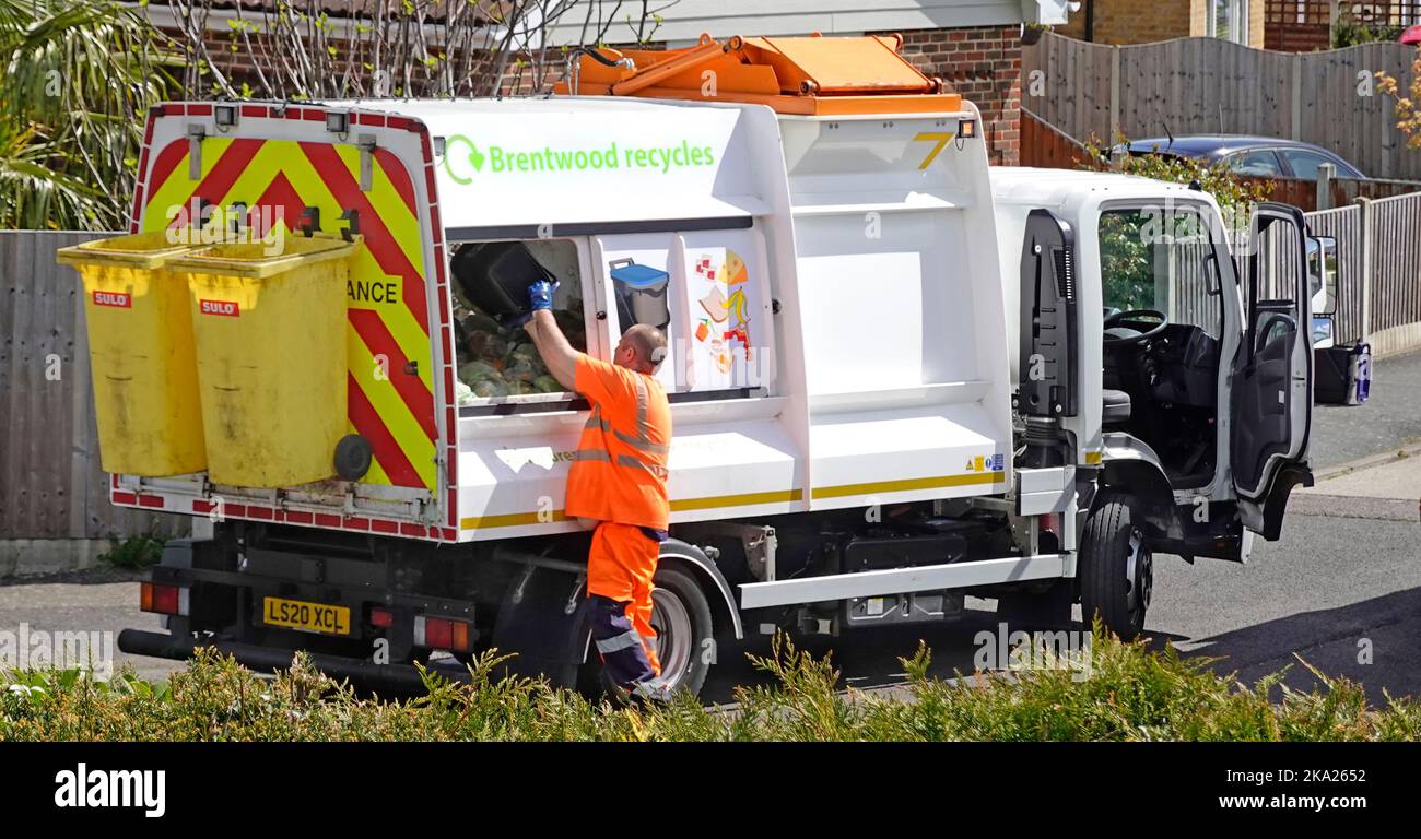 Residuos de alimentos reciclando camión conductor de alta visibilidad ropa se detiene para vaciar el contenedor de cadáveres de la casa en la recogida camión carretera residencial Essex Inglaterra Reino Unido Foto de stock