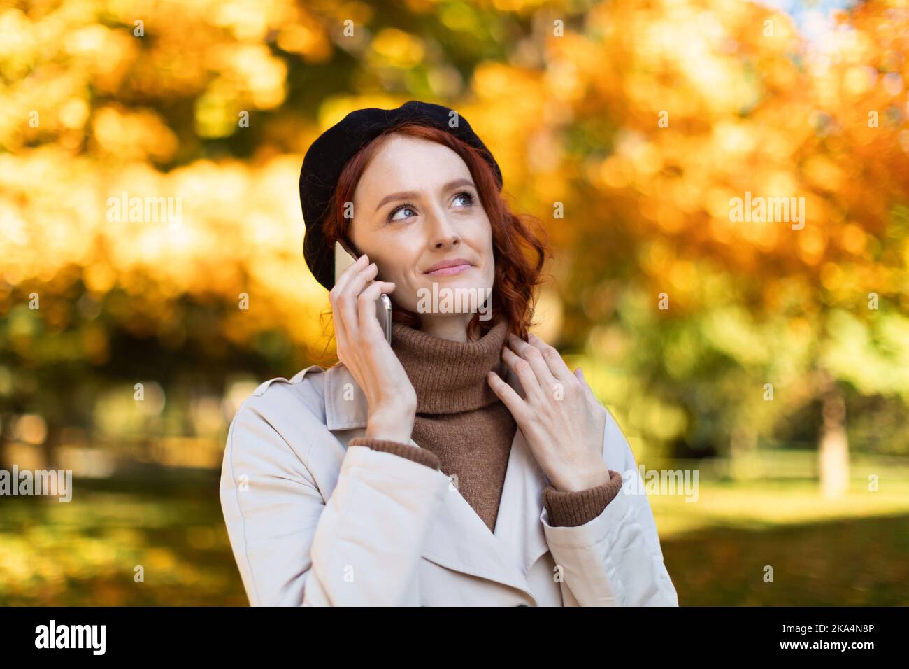 Sonriendo joven de ensueño europeo señora de pelo rojo con chubasquero y  sombrero, llamadas por teléfono inteligente, mirar el espacio de copia  Fotografía de stock - Alamy