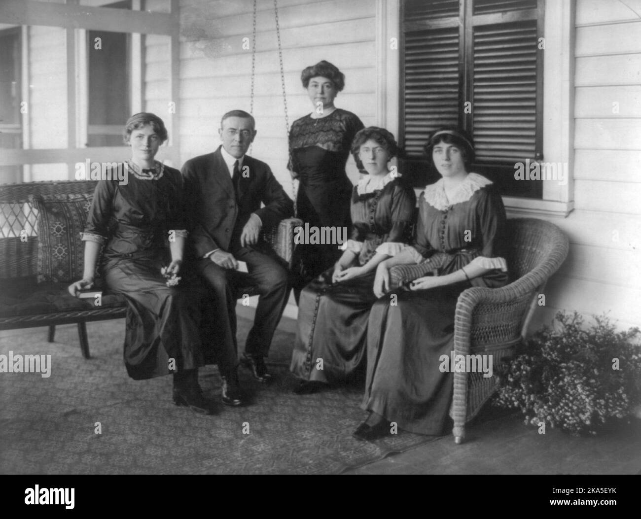Woodrow Wilson, sentado en un columpio en el porche, mirando al frente, con su esposa y tres hijas. De izquierda a derecha: Margaret Wilson, su primera esposa Ellen Axson Wilson, Jessie Wilson y Eleanor Wilson. Foto de stock