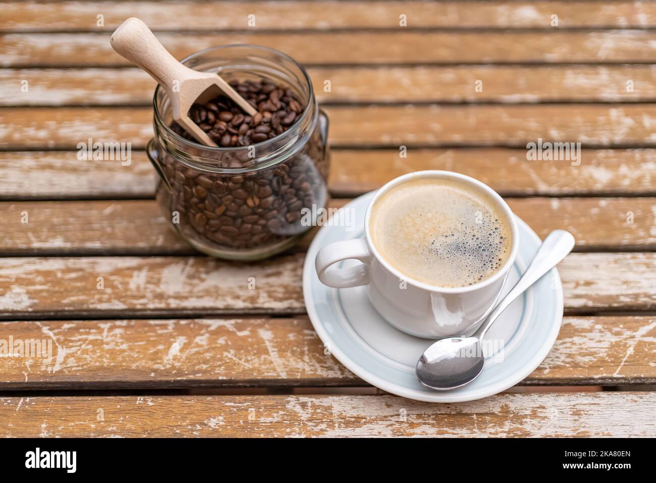 Taza de café con tarro de cristal lleno de granos de café sobre una mesa de  madera de jardín Fotografía de stock - Alamy