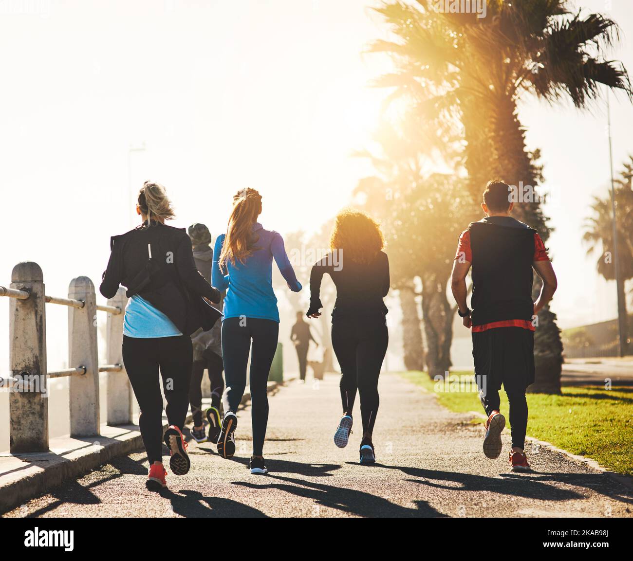 Su salud depende de ello. Imagen trasera de un grupo de fitness corriendo por el paseo marítimo. Foto de stock
