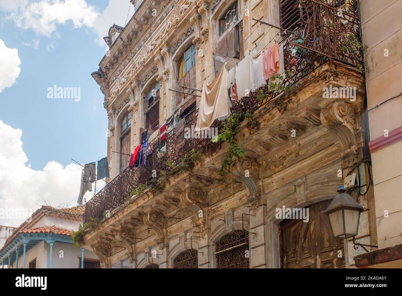Secar la ropa en una línea de ropa. Los artículos textiles cuelgan de un balcón en la fachada de un edificio desgastado y desgastado en el cit de la capital cubana Foto de stock